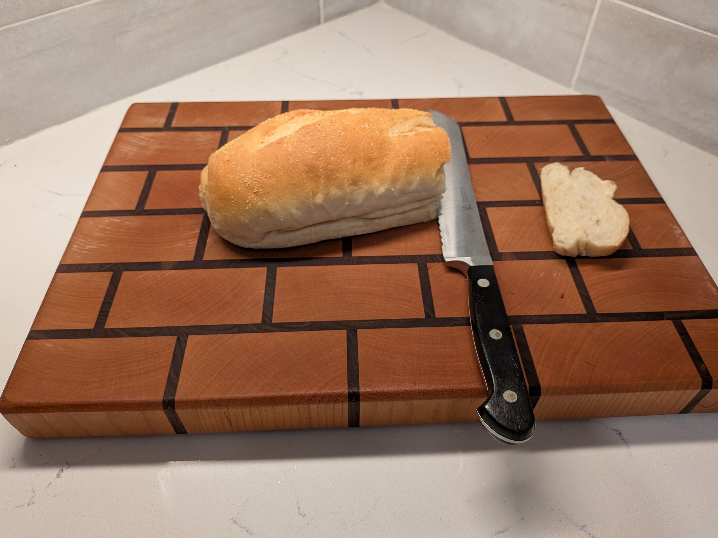End-grain cutting board in a brick pattern with fresh bread